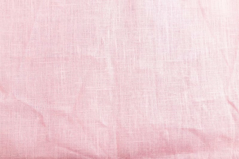 Fragment of smooth pink linen tissue. Top view, flat lay, natural textile background and texture