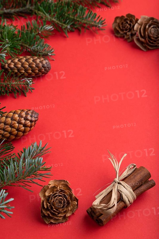 Christmas or New Year composition. Decorations, box, cinnamon, cones, fir and spruce branches, cup of coffee, on a red paper background. Side view, copy space