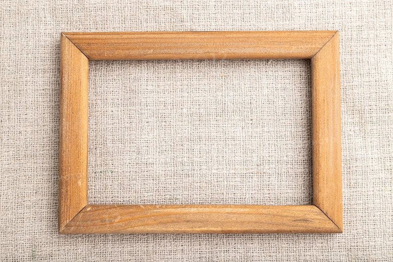 Wooden frame on smooth linen tissue. Top view, flat lay, natural textile background and texture