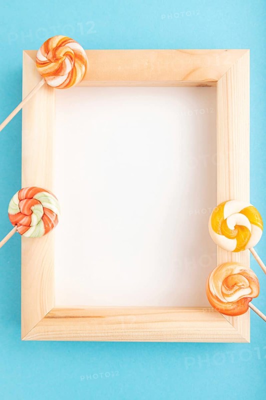 Composition with lollipops and wooden frame on blue pastel background. copy space, top view, flat lay, template