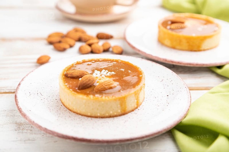 Sweet tartlets with almonds and caramel cream with cup of coffee on a white wooden background and green textile. side view, close up, selective focus