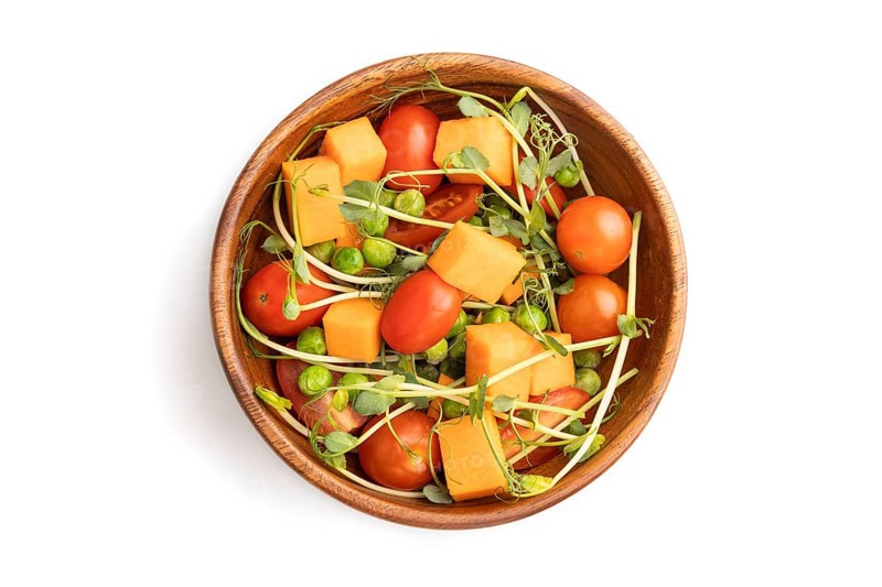 Vegetarian vegetable salad of tomatoes, pumpkin, microgreen pea sprouts isolated on white background. Top view, flat lay, close up
