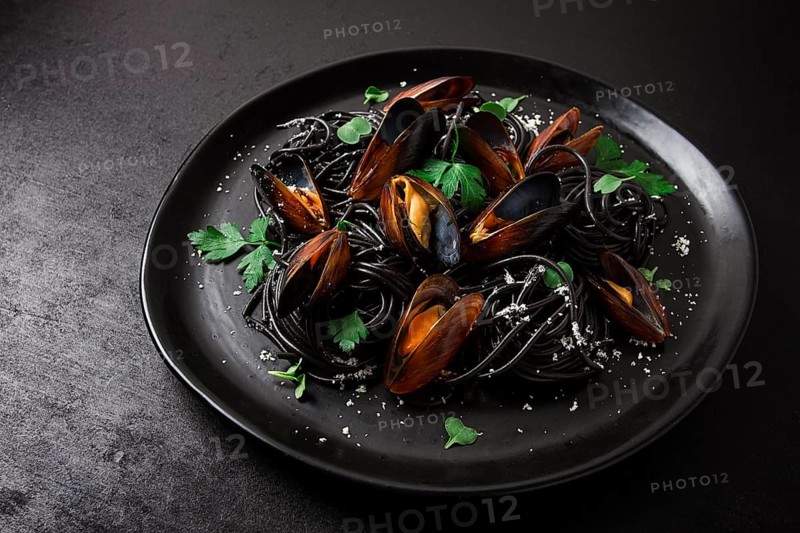 Spaghetti with black squid, black pasta, with boiled mussels, on a black plate, with parsley and parmesan cheese, close-up, selective focus, no people