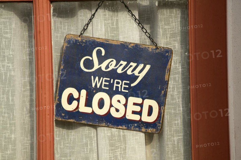 Old fashioned 'Sorry we're Closed' sign in window of closed down village shop