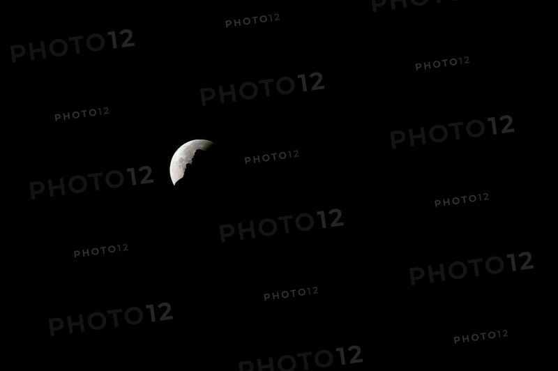 The moon disappears behind a mountain silhouette, taken in the Swiss mountains, Switzerland, Europe