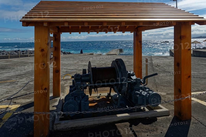 Historic whale towing facility and winch under a wooden canopy with a view of the sea and blue sky, whale station and factory, Capelas, Sao Miguel Island, Azores, Portugal, Europe