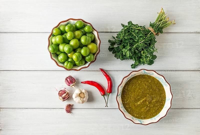 Tkemali sauce, traditional Georgian cuisine, green cherry plum, with ingredients for sauce, cilantro, mint, hot pepper, garlic, on a white wooden table, close-up, rustic, food background, no people, selective focus, sauce, green sauce, tkemali, georgian cuisine, homemade