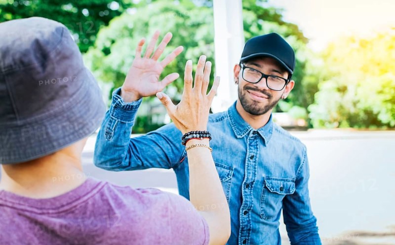 Two smiling friends shaking hands on the street. Friends shaking hands outdoors. Concept of two friends greeting each other with a handshake on the street