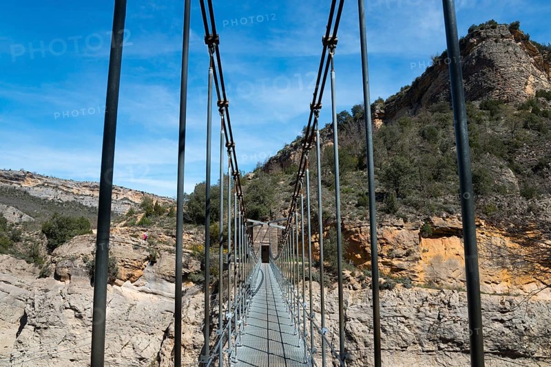 A suspension bridge leads through a rocky gorge with steep walls and green vegetation, Noguera Ribagorçana Mont-rebei Natural Park, Montsec mountain range, Noguera Ribagorçana river, Lleida province, Catalonia, Aragon, Spain, Europe