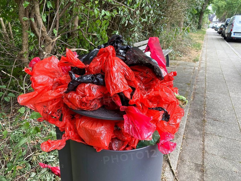 Overflowing rubbish bin, with lots of rubbish, overfilled with dog faeces bags, on a wall path in Essen, North Rhine-Westphalia, Germany, Europe