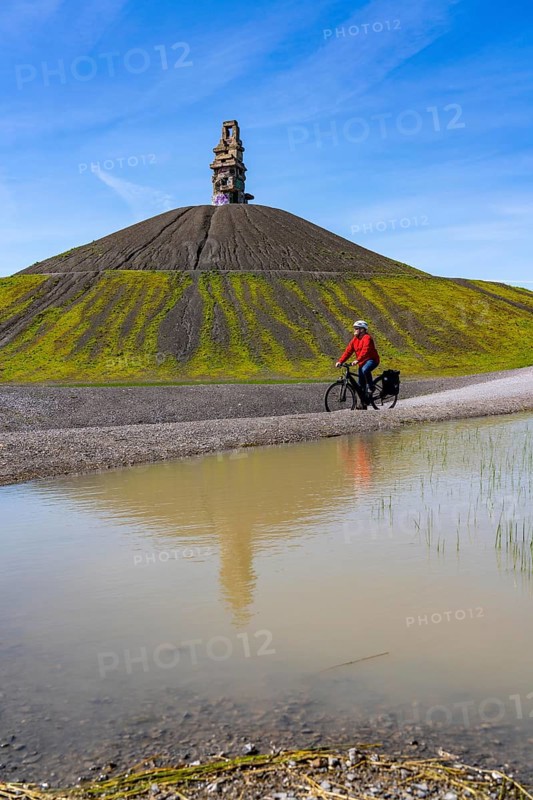 Cyclist on the Rheinelbe spoil tip in Gelsenkirchen, 100 metre high spoil tip, landscape park, with the sculpture Himmelsleiter, made of concrete parts of the former Rheinelbe colliery, Gelsenkirchen, North Rhine-Westphalia, Germany, Europe