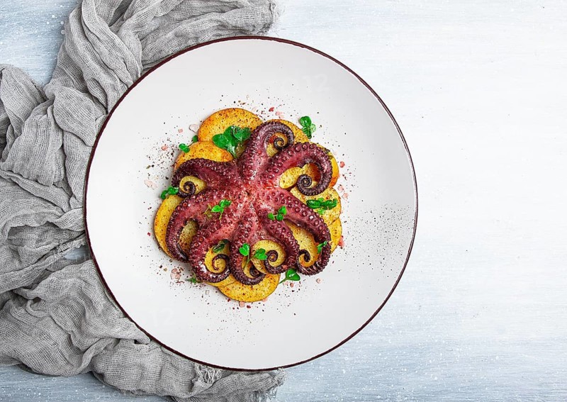 Octopus with potatoes and spices, on a light plate, top view, no people, homemade, close-up