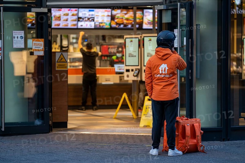 First day of the Christmas lockdown in the Corona crisis, shopping alleyway Schildergasse, in the city centre, Lieferando delivery driver waiting for a delivery in front of a Burger King branch, in Cologne, North Rhine-Westphalia, Germany, Europe