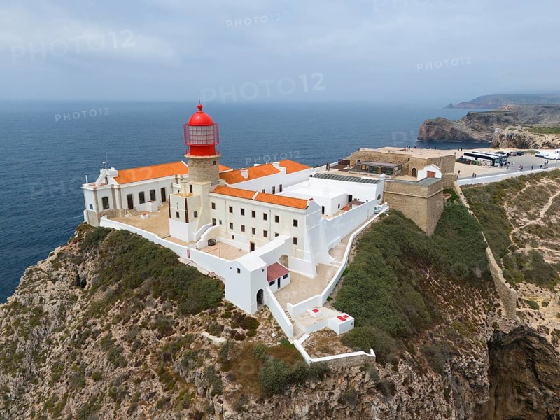 A red lighthouse on a rocky cliff, surrounded by white buildings, overlooking the ocean, aerial view, lighthouse, Cabo de São Vicente, Cape St Vincent, Cape St Vincent, Sagres, Portugal, Europe