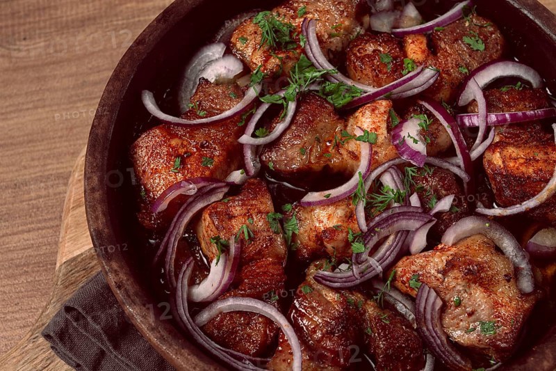 Fried meat, pork kebab, ketsi in a clay pan, with red onions and herbs, homemade, no people