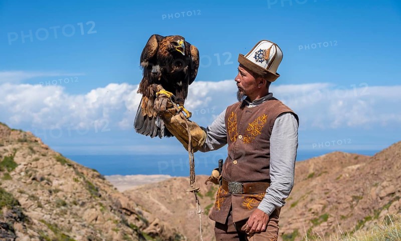 Traditional Kyrgyz eagle hunter with eagle in the mountains, near Kysyl-Suu, Kyrgyzstan, Asia