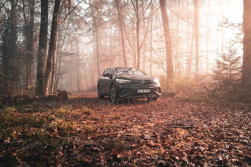 A Volkswagen stands on a path in an autumnal forest, surrounded by morning mist and golden light, electric car VW ID5, Deer Carsharing, Gechingen, Black Forest, Germany, Europe