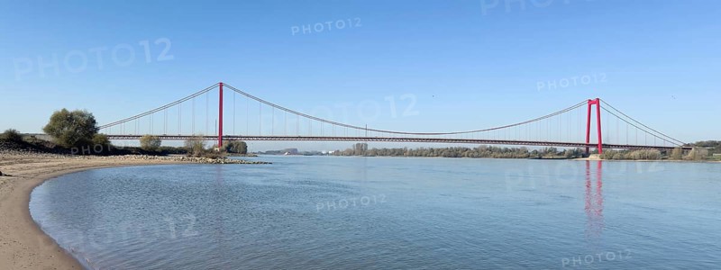 Panorama view from the left bank of the Rhine, western bank of the Rhine, of an earth-anchored suspension bridge with two abutments and red steel piers nicknamed the Golden Gate of the Lower Rhine over the River Rhine, with a total length of 1228 metres the longest suspension bridge in Germany, Emmerich, North Rhine-Westphalia, Germany, Europe
