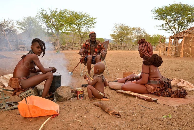 Chief Hikuminue Kapika, tribal leader of the Namibian Himba people, sitting with his family at a fire in his kraal, Omuramba, Kaokoland, Kunene, Namibia, Africa