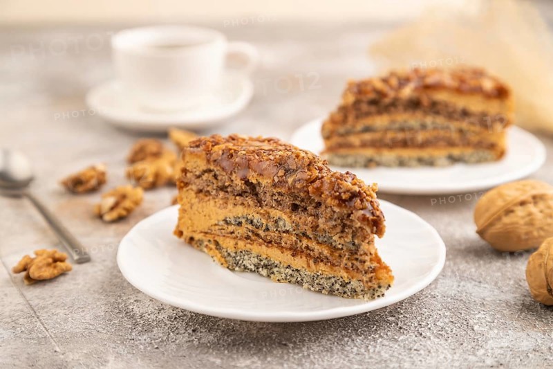 Walnut and hazelnut cake with caramel cream, cup of coffee on brown concrete background. side view, selective focus