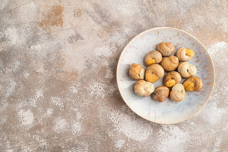 Grape (Burgundy) snails with butter and cheese on brown concrete background. Top view, flat lay, copy space