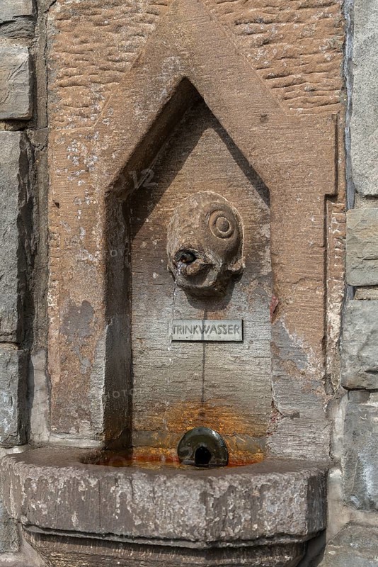 Meersburg on Lake Constance, fish spits water jet, inscription drinking water, fountain, close-up, light-coloured red sandstone, Baden-Württemberg, Germany, Europe
