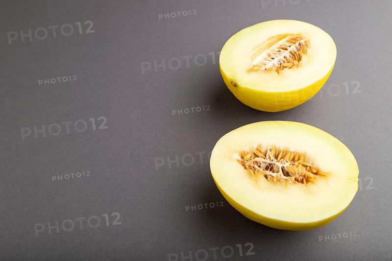 Sliced ripe yellow melon on gray pastel background. Side view, copy space. harvest, women health, vegan food, concept, minimalism