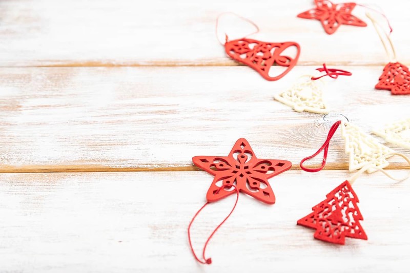 Christmas or New Year composition. Decorations, red stars, bells, on a white wooden background. Side view, copy space, selective focus