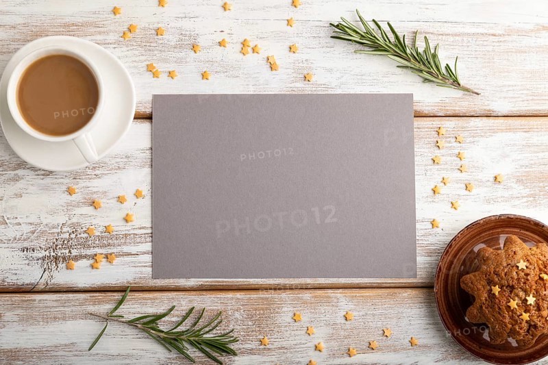 Gray paper sheet mockup with cup of coffee and cake on white wooden background. Blank, top view, flat lay, still life