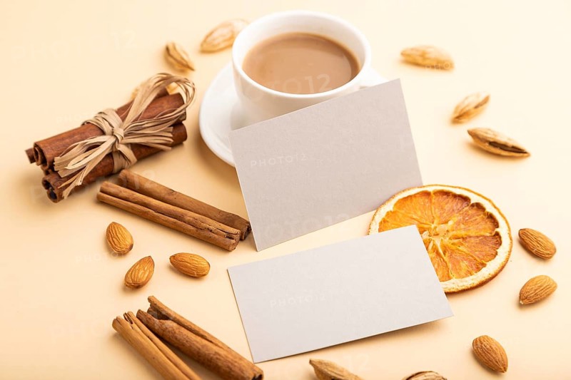 Composition of gray paper business cards, almonds, cinnamon and cup of coffee. mockup on orange background. Blank, side view, still life, copy space