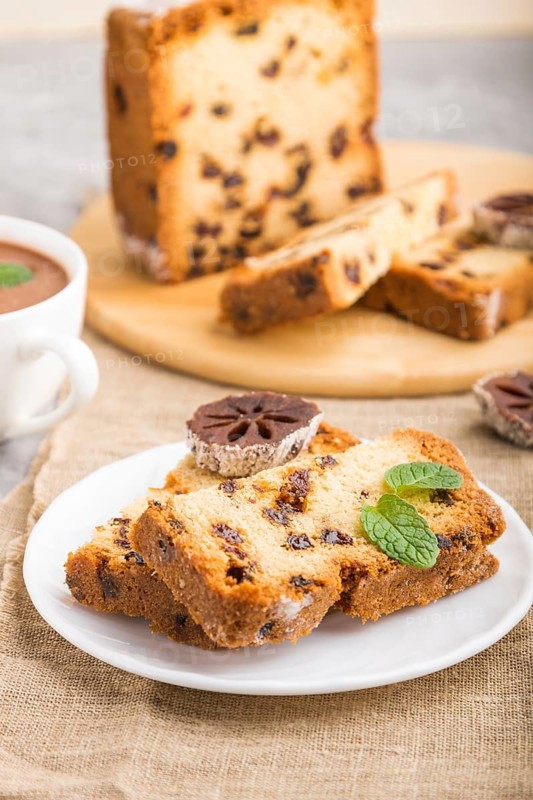 Homemade cake with raisins, dried persimmon and a cup of hot chocolate on a gray concrete background and linen textile. Side view, close up, selective focus