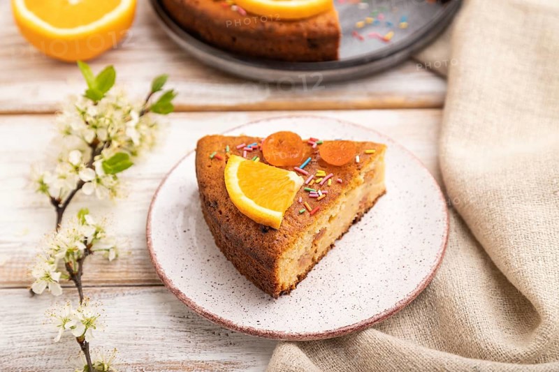 Orange cake and a cup of coffee on a white wooden background and linen textile. Side view, close up, selective focus