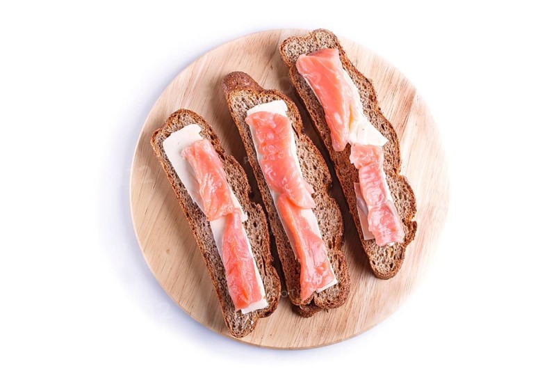Smoked salmon sandwiches with butter on wooden board, isolated on white background. close up