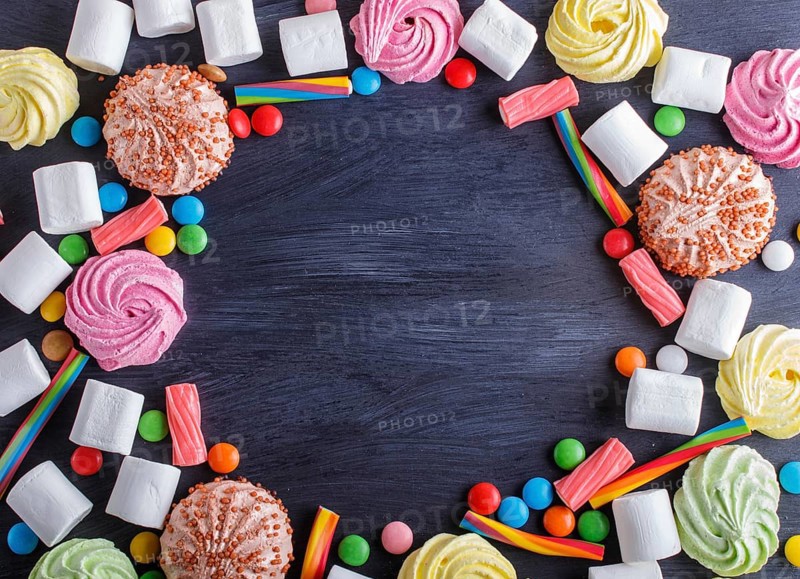 Colorful frame of multicolored candies on black wooden background. Circle copy space, top view, flat lay