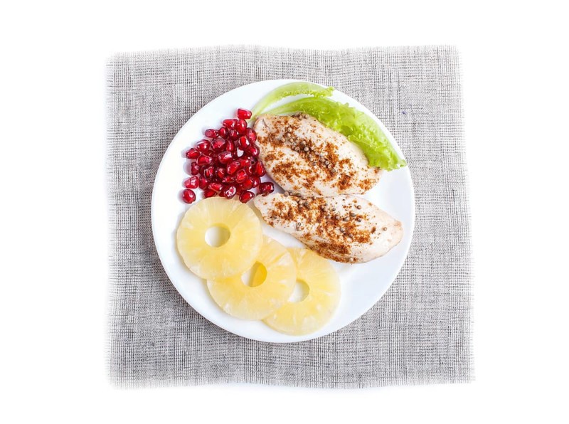 Fried chicken fillets with lettuce, pineapple and pomegranate seeds isolated on white background, top view