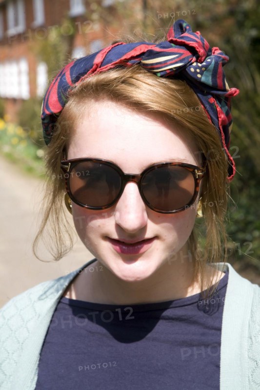 Model released head and shoulders portrait of teenage girl wearing sunglasses and head scarf outdoors, UK