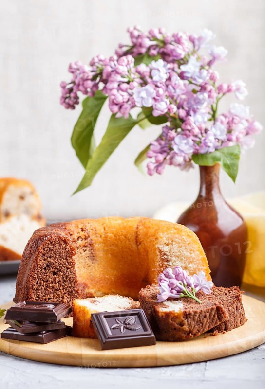 Cakes with raisins and chocolate and a cup of coffee. lilac flowers on a gray concrete background, side view
