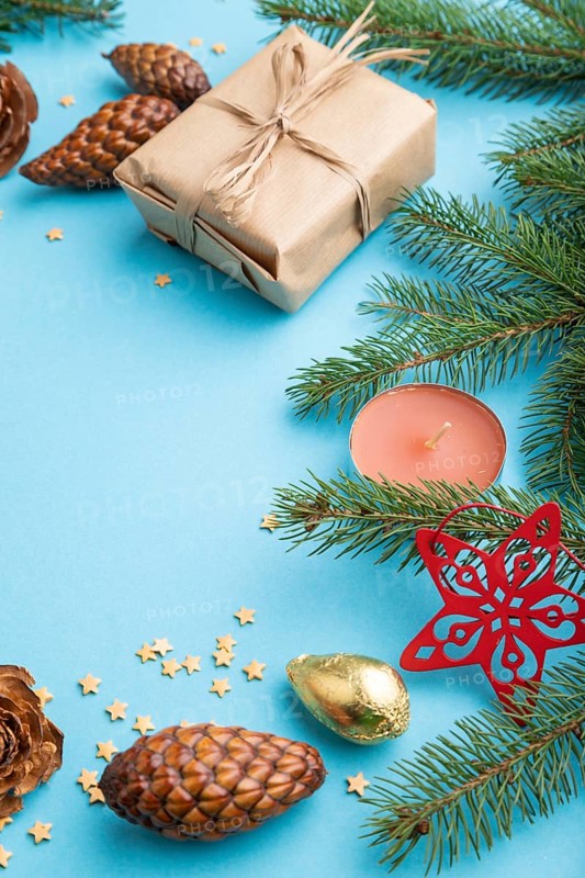 Christmas or New Year composition. Decorations, box, cinnamon, cones, fir and spruce branches, cup of coffee, on a blue paper background. Side view, copy space