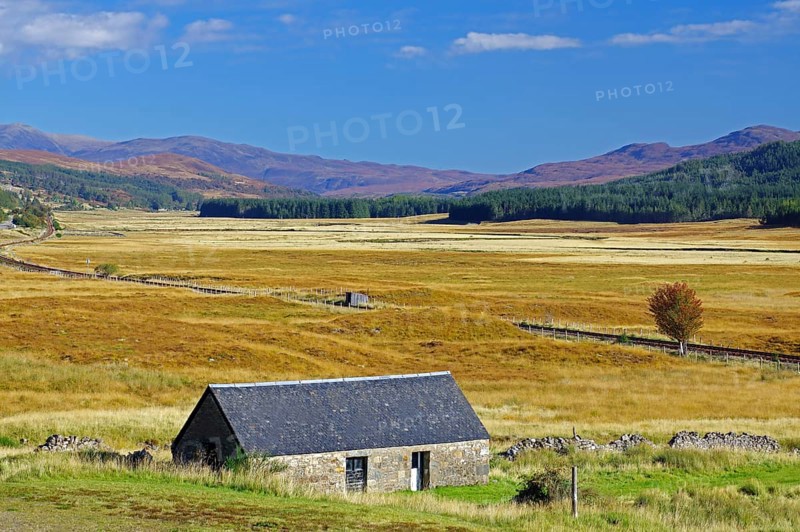 Small stone house on a wide, grassy plain under a clear blue sky, autumn, October, Highlands, railway line Inverness to Kyle of Lochals, Scotland, Great Britain