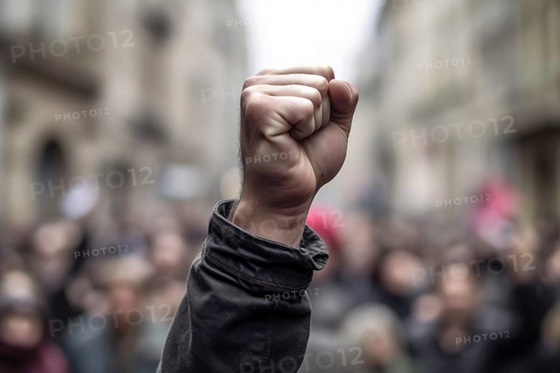 Man's raised fists with blurry crowd of rioting people in background. KI generiert, generiert AI generated