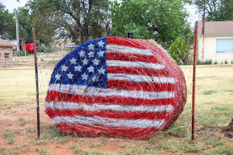 Laverne, Oklahoma, An American flag is painted on a hay bale as part of a patriotic display in front of a rural Oklahoma home