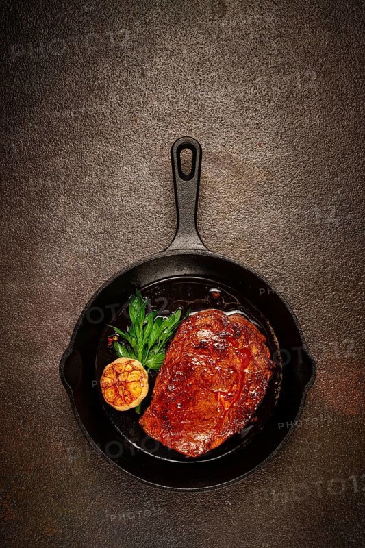 Grilled rib eye steak, in a cast-iron skillet, top view, homemade, no people