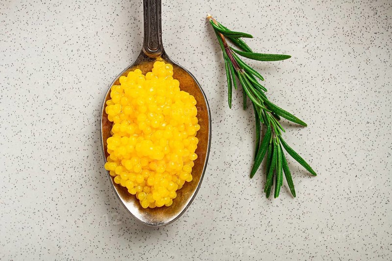 Yuzu caviar is pearly, on a spoon, top view, light background, no people.
