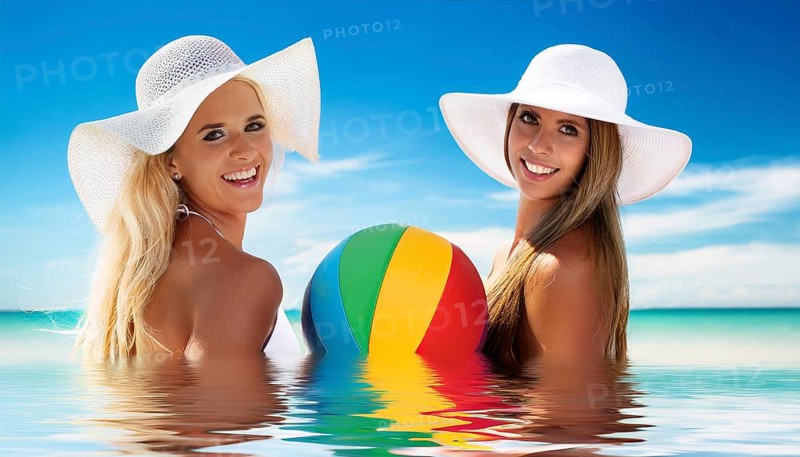 Two young woman in sun hats playing with a beach ball on the beach in the Caribbean
