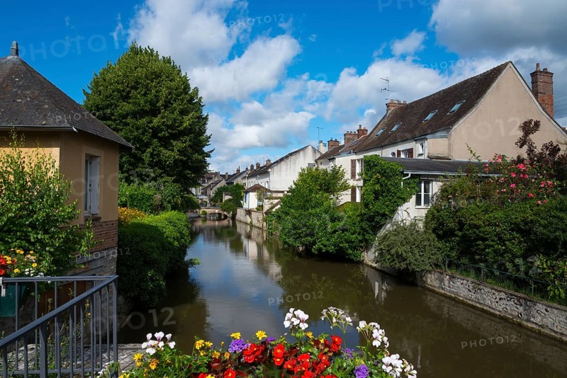 Kleines Dorf mit Häusern am Fluss, blauer Himmel, Blumen auf einer Brücke, friedliche Atmosphäre, Nemours am Fluss Loing, Département Seine-et-Marne, Region Île-de-France, Ile-de-France, Frankreich