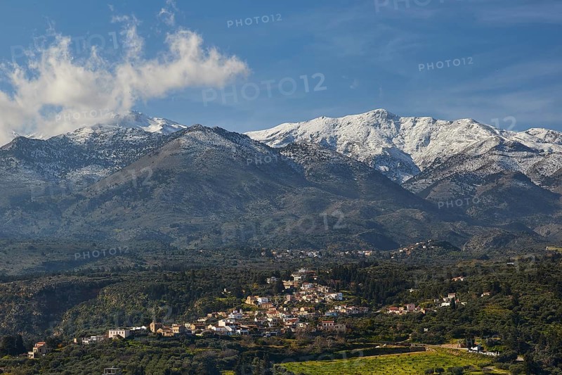 Small village in hilly landscape under snow-capped mountains and blue sky, vineyard, olive groves, Lefka Ori, White Mountains, mountain massif, West, Crete, Greece, Europe