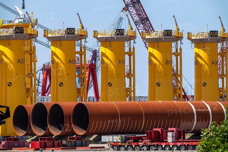 Transhipment centre for offshore wind turbines, which are transported here by the manufacturer and then shipped by special ships to the construction sites of the wind farms in the North Sea, here, yellow, so-called Transition Pieces Jackets, which are mounted on the monopile foundations driven into the seabed, on which the actual wind turbine is then mounted, in the port area of Vlissingen-Oost, Netherlands