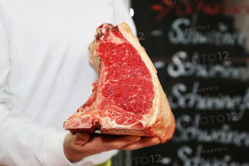 Butcher holds a dry aged T-bone steak in his hand