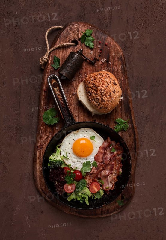 Fried egg, with bacon and vegetables, in a cast-iron frying pan, top view, homemade breakfast