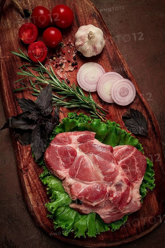Raw pork steak, two pieces, on a wooden background